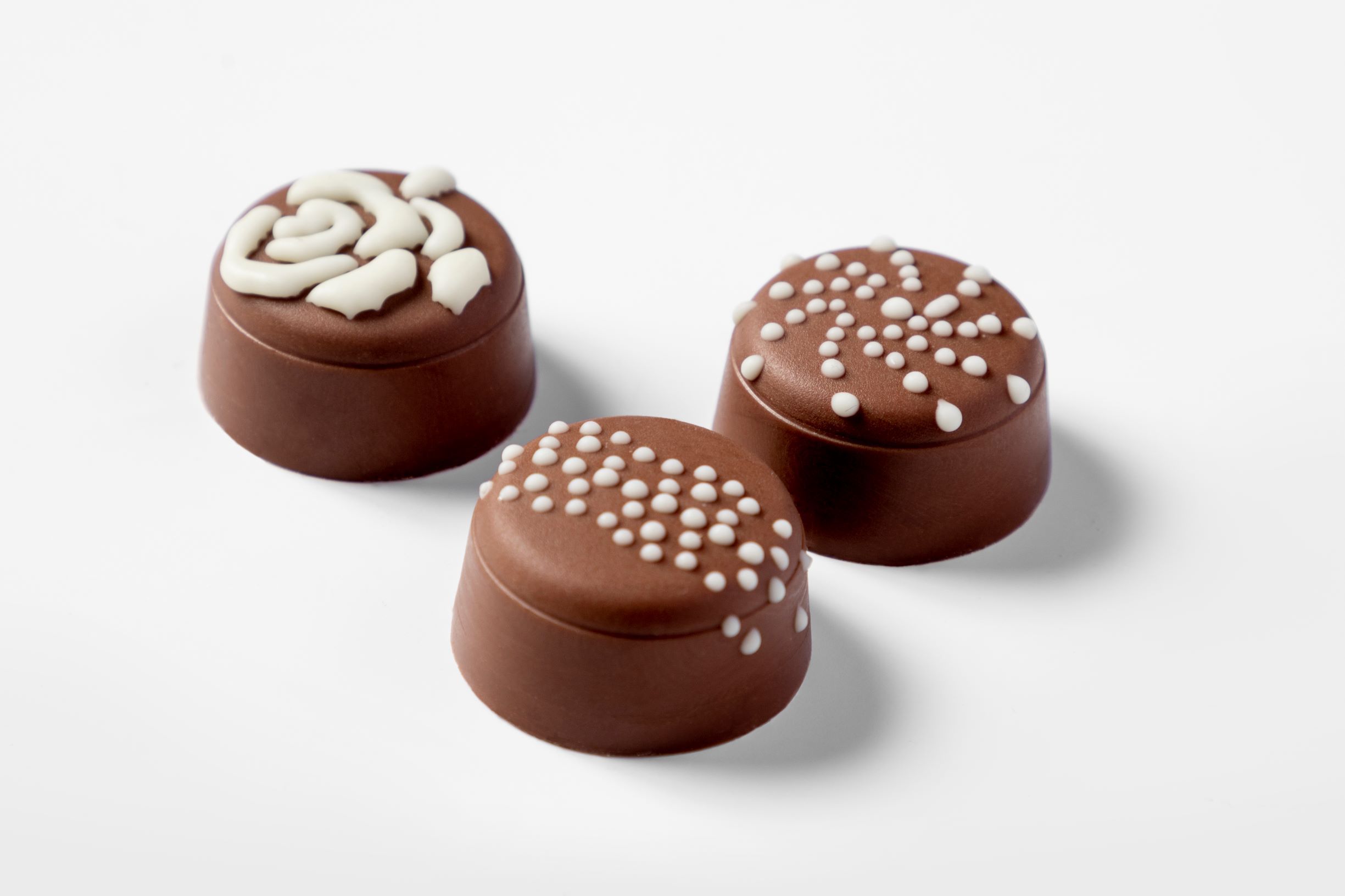 Three milk chocolate pralines decorated with white chocolate by FoodJet chocolate depositor
