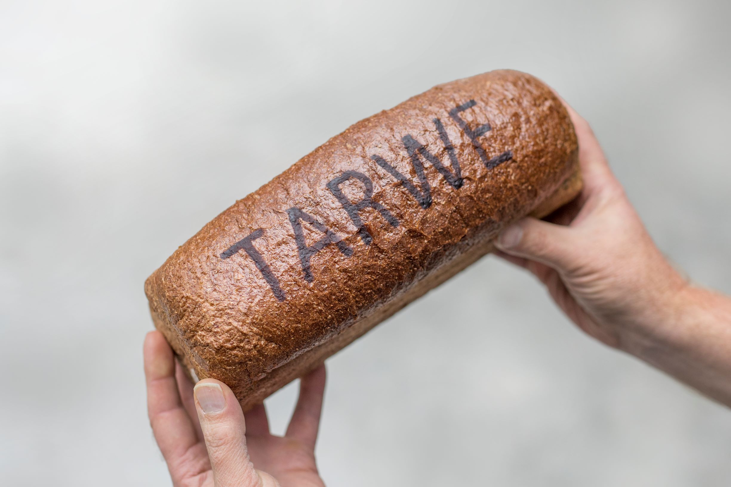 Two hands holding a loaf of bread decorated with RudinJet edible paste printed with FoodJet depositor