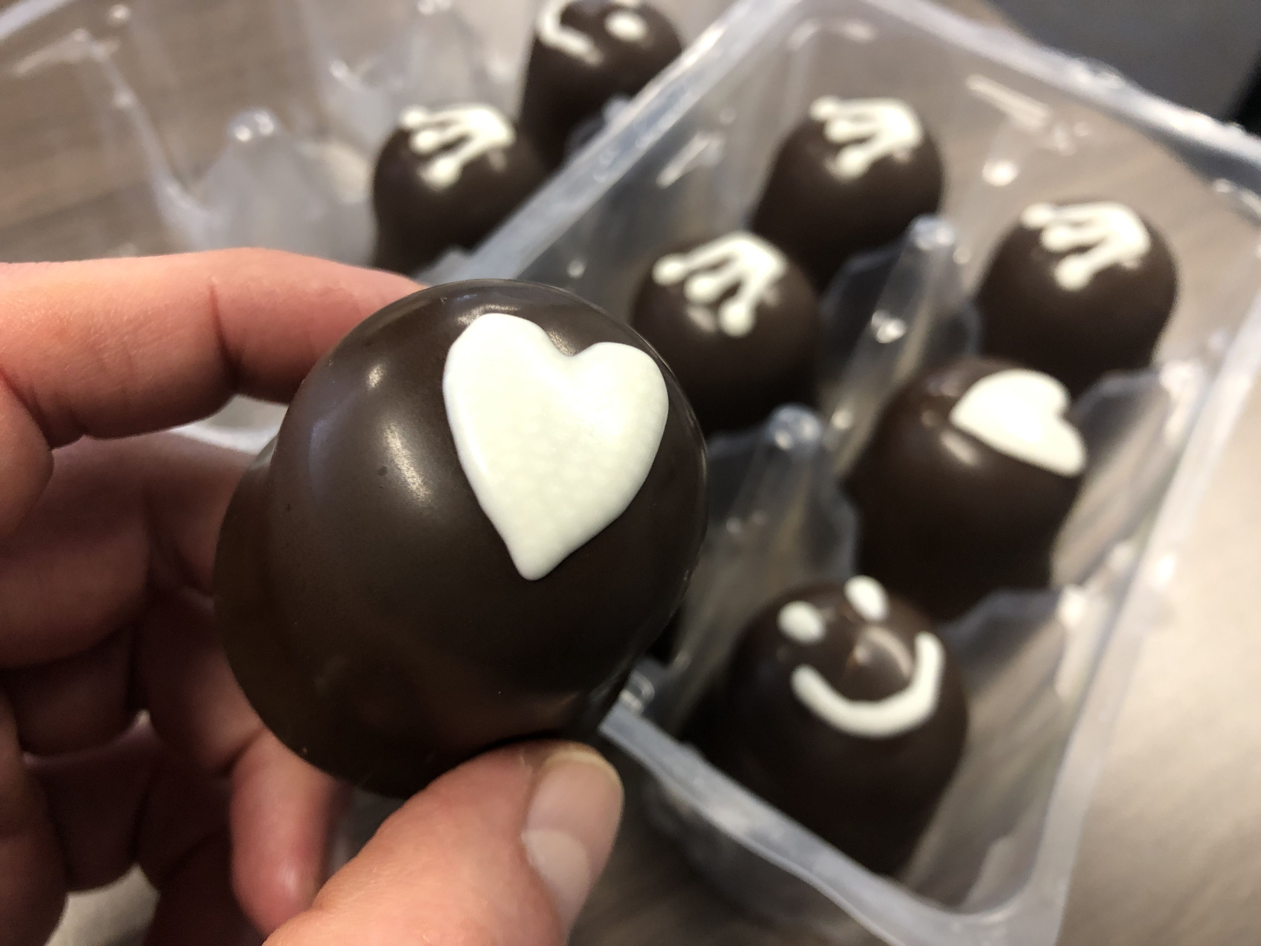 Hand holding mellow cake decorated with white chocolate heart printed with FoodJet chocolate depositor