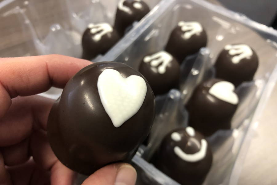 Hand holding a milk chocolate mellow with white chocolate decoration