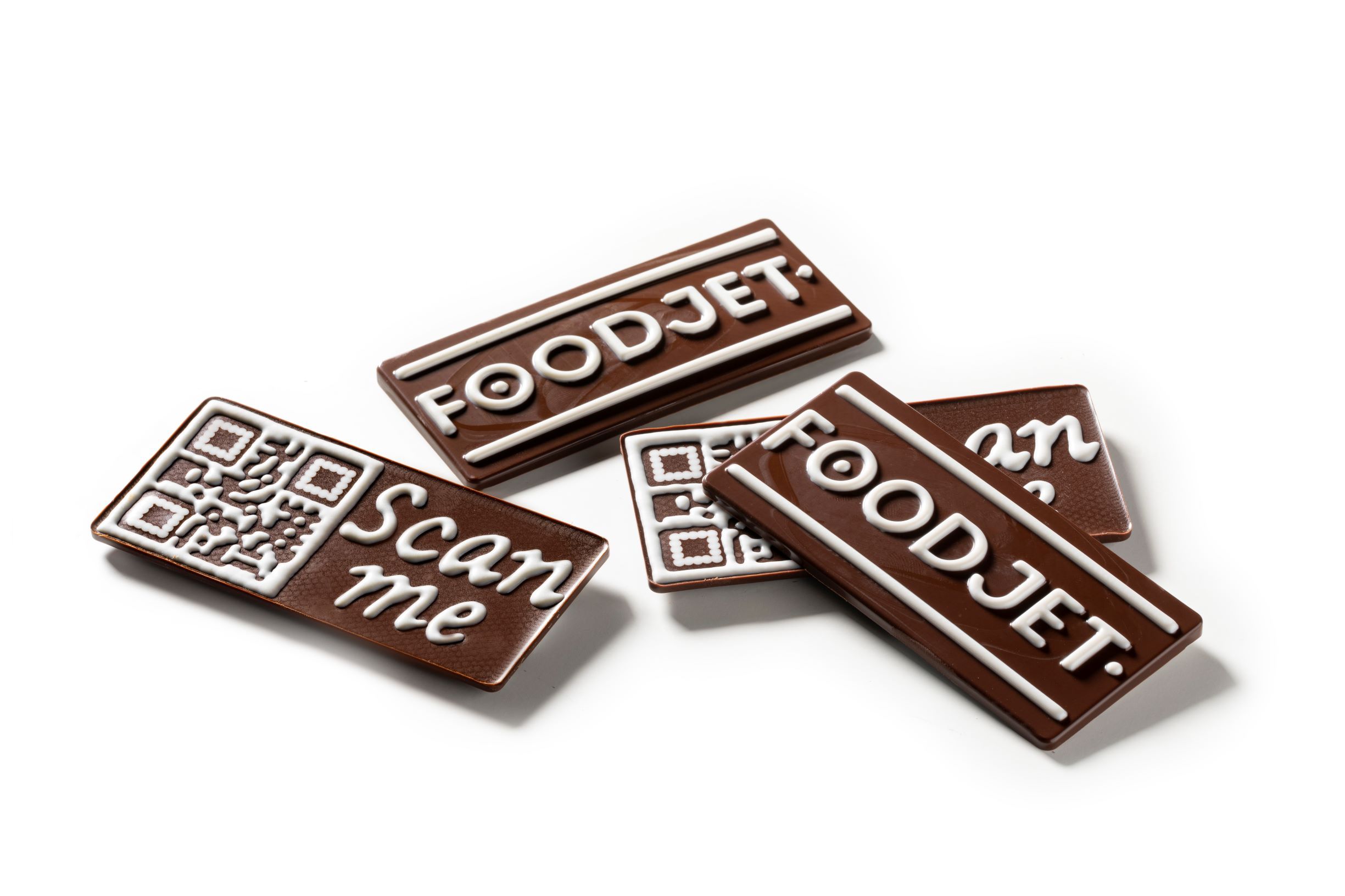 Four milk chocolate bars with white chocolate decorations made with FoodJet chocolate depositor