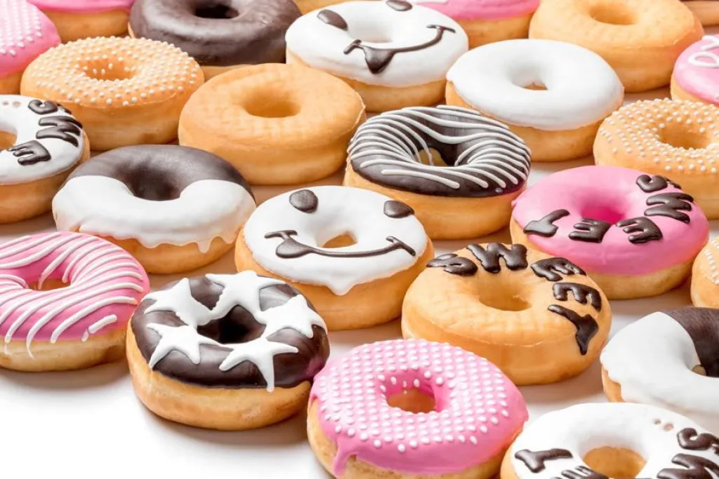 Donuts decorated with pink, white and dark chocolate compound, with dots, stars and lettering