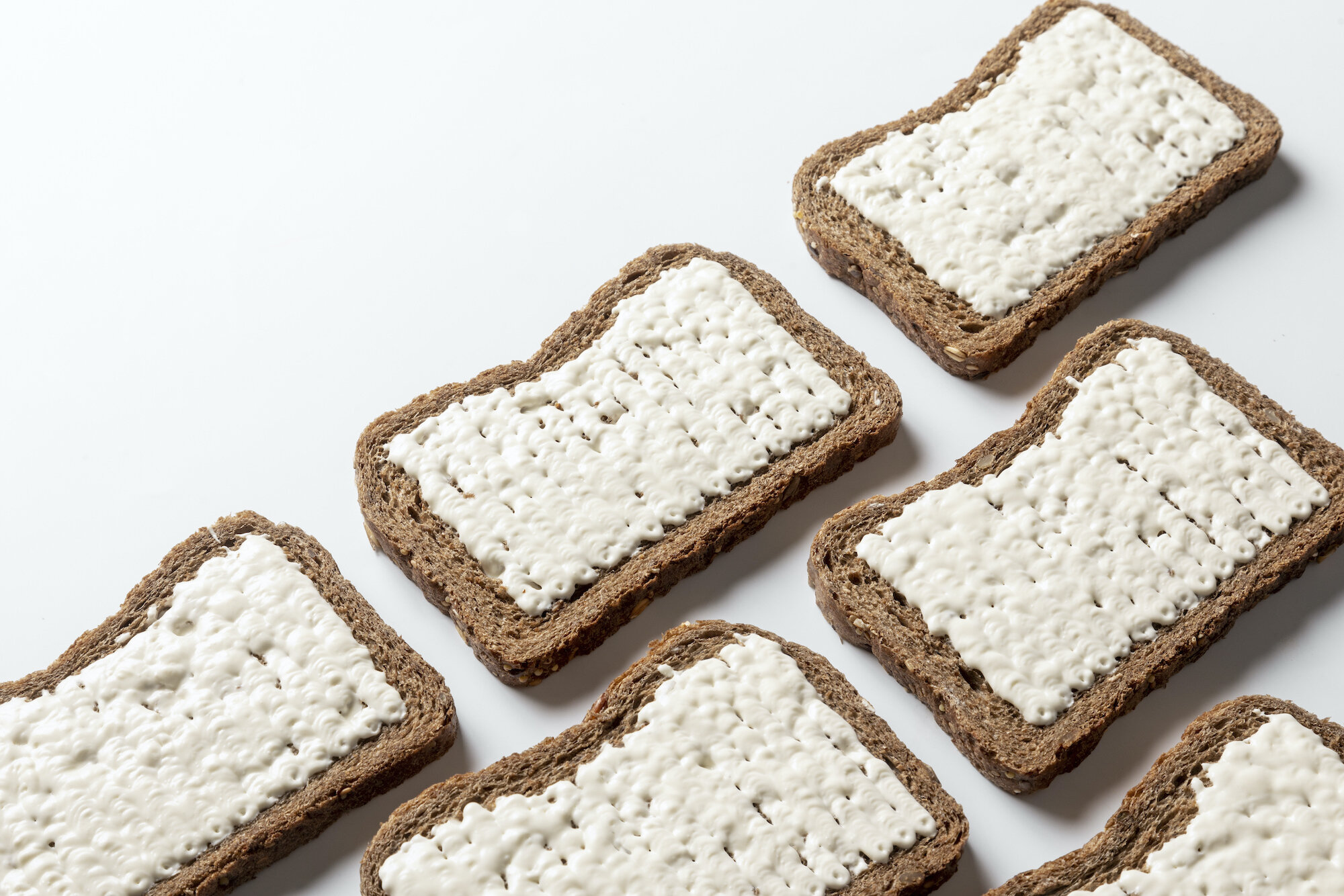 Various slices of bread surface covered with butter by a FoodJet cream depositor