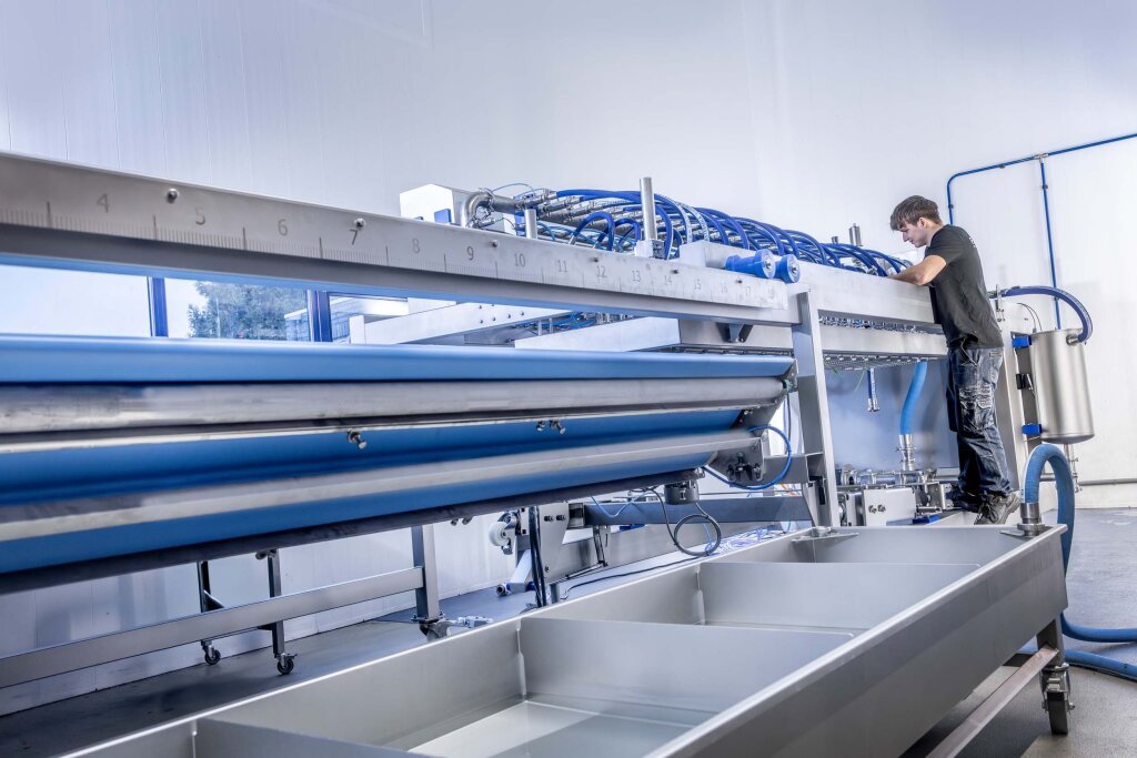 Technician working on a FoodJet depositing line with a stainless steel conveyor