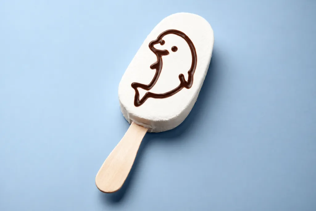 White ice cream bar on a stick decorated with a chocolate dolphin outline