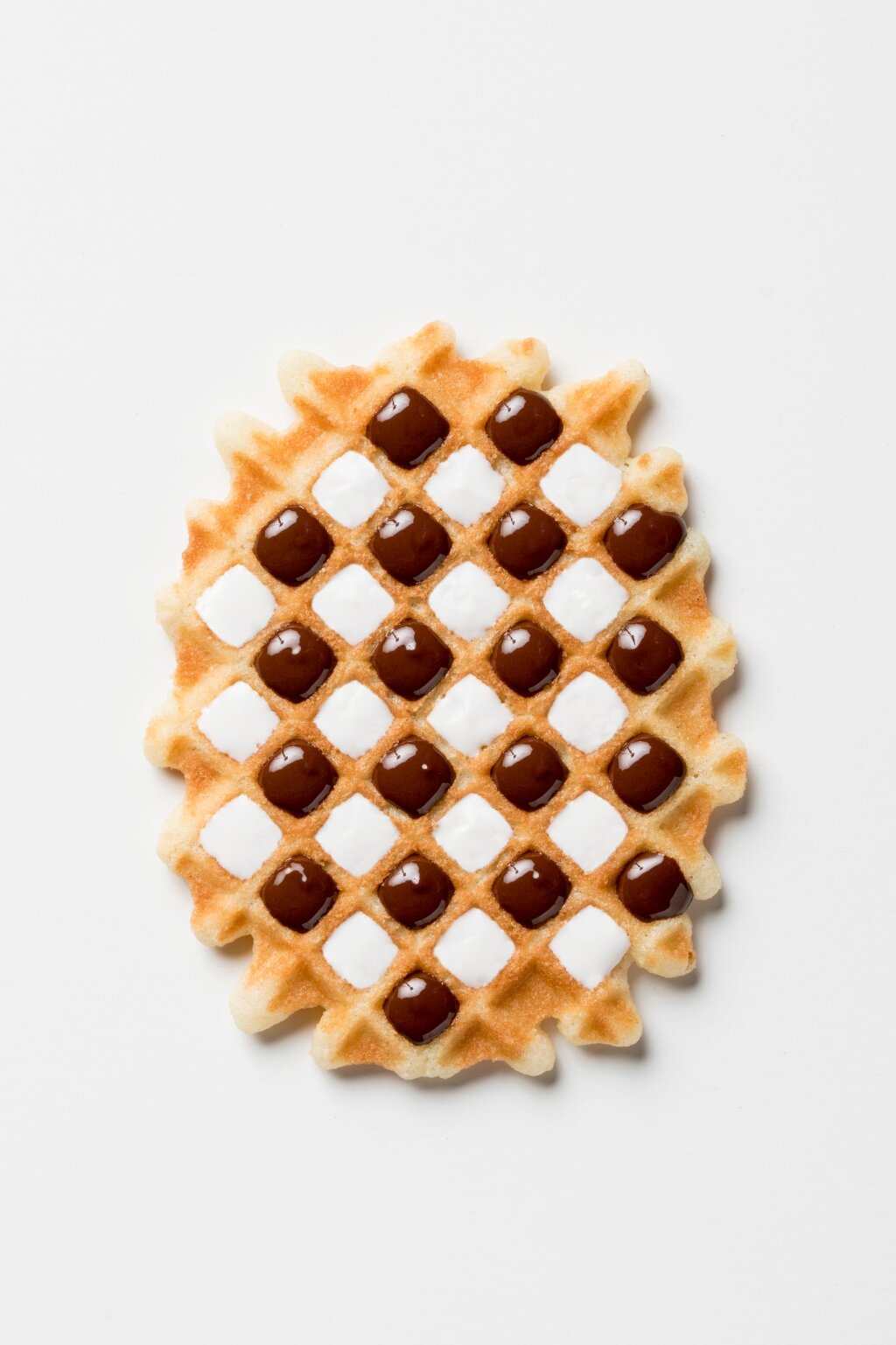 Waffle with dark and white compound in alternating cavities, forming a checkerboard pattern
