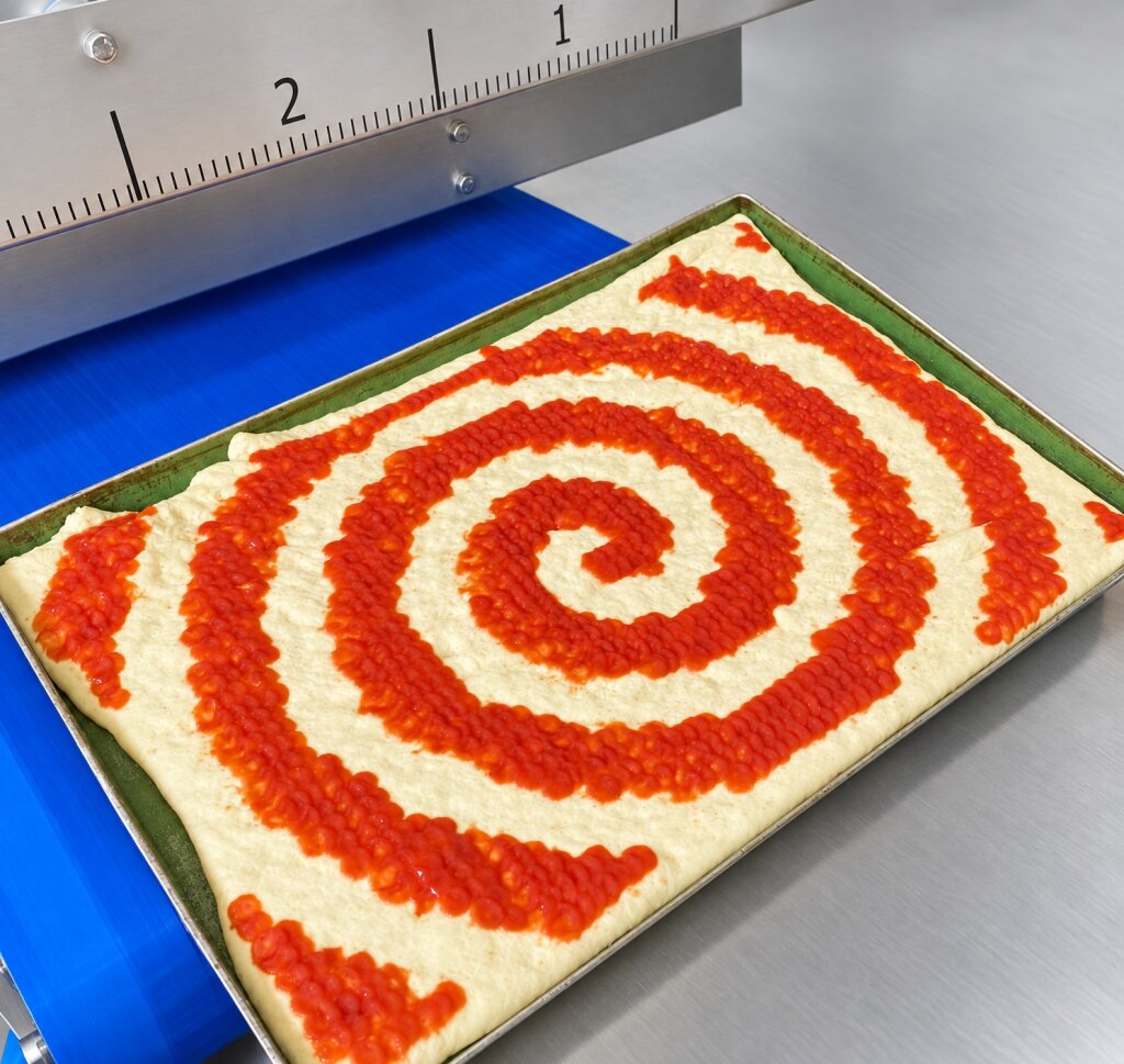 Pizza base with a spiral of tomato sauce on a baking tray