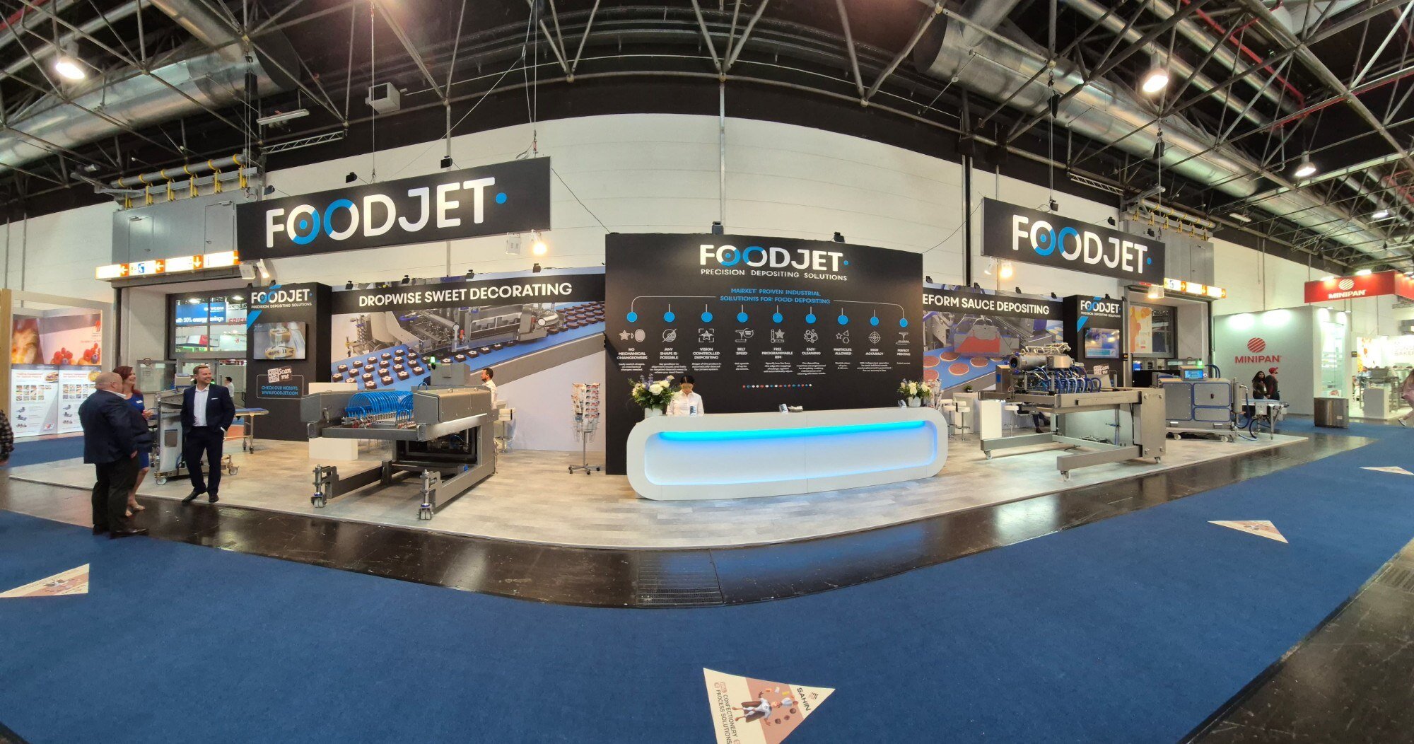 Panorama of the FoodJet corner stand at iba 2025 with depositing lines and a white reception desk